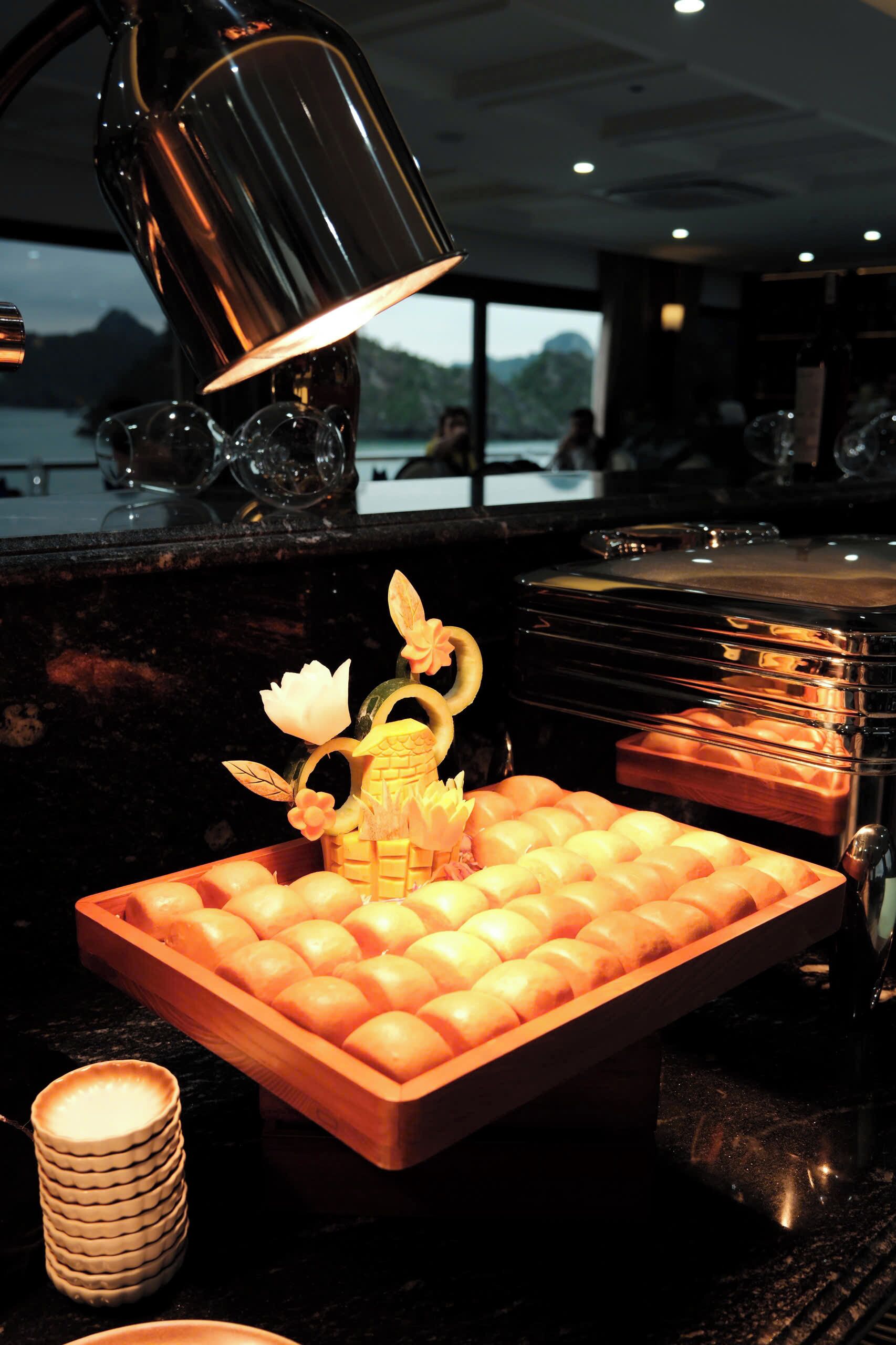 A buffet setup with a decorative centerpiece, a stack of plates, and a glass container.