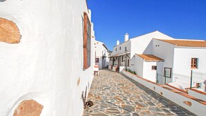 Una estrecha calle adoquinada bordeada por edificios blancos con techos de tejas rojas.