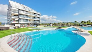 A modern hotel with a large swimming pool, multiple balconies, and a tropical landscape. - Stunning apartment in Cabanes with swimming pool (Cabanes)