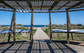 A wooden boardwalk leading to a beach with a pergola structure providing shade. - Stunning apartment in Cabanes with swimming pool (Cabanes)