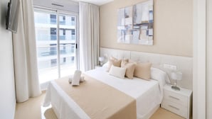 A hotel room with a large bed, a flat-screen TV mounted on the wall, a bedside table with a lamp, and a window with curtains. - Stunning apartment in Cabanes with swimming pool (Cabanes)