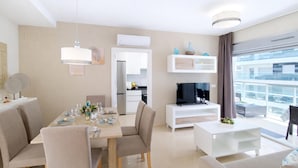 A modern living room with a dining area, a TV, and a balcony with a city view. - Stunning apartment in Cabanes with swimming pool (Cabanes)