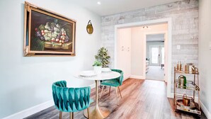 A dining area with a round table, teal chairs, and a framed painting on the wall. - The Montecito Midpoint — spacious — 100" TV (Phoenix)