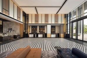 Een moderne lobby met een geruit vloerkleed, een bank, een salontafel en een receptiebalie.