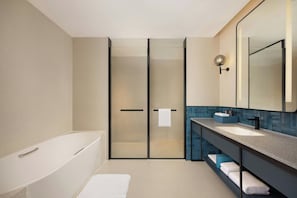 A modern bathroom with a bathtub, a glass shower enclosure, a vanity with a sink, and a large mirror. - Four Points by Sheraton Chongqing Jiangjin (Chongqing)