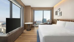 Et moderne hotelværelse med en stor seng, et fjernsyn på indbygget hylde, et lille bord og en stol.