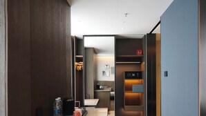 Et moderne hotelværelse med en marmor bordplade, minibar, indbygget skab og et lille siddeområde.