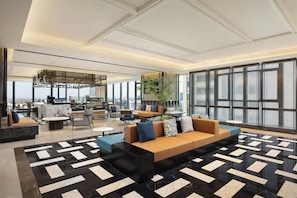 A spacious lobby with a modern sofa, a patterned floor, and large windows offering a city view. - Four Points by Sheraton Hefei, Qirui (Hefei)