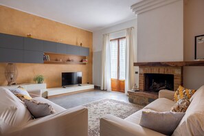 Ein Wohnzimmer mit Kamin, Sofa, Fernseher und Bücherregal.