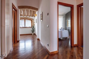 Ein Flur mit Holzboden, einem Fenster mit Ausblick und einer Tür zu einem Zimmer mit Bett und Badezimmer.