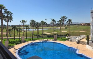 A swimming pool with a view of a golf course and palm trees. - Cozy apartment in Murcia (Murcia)