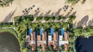 Luchtbeeld van een resort met meerdere bungalows, een zwembad en omliggend groen.