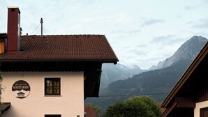 A building with a tiled roof, a chimney, and a sign indicating it is a restaurant. - Between blossoms & mountains, welcome to the beehive (Fischen im Allgäu)