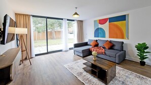Een moderne woonkamer met een grijze bank, een houten salontafel en een groot abstract schilderij aan de muur.