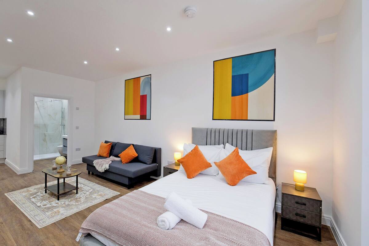 Une chambre d’hôtel moderne, dotée d’un grand lit, d’un canapé, d’une table basse et d’œuvres d’art accrochées aux murs.