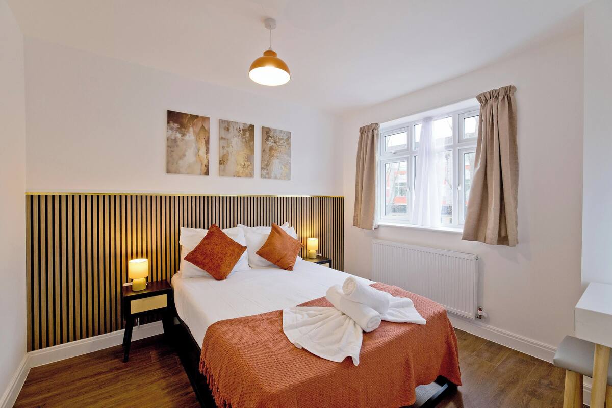 Une chambre d’hôtel avec un lit, des lampes de chevet, une fenêtre avec des rideaux et des œuvres d’art accrochées au mur.