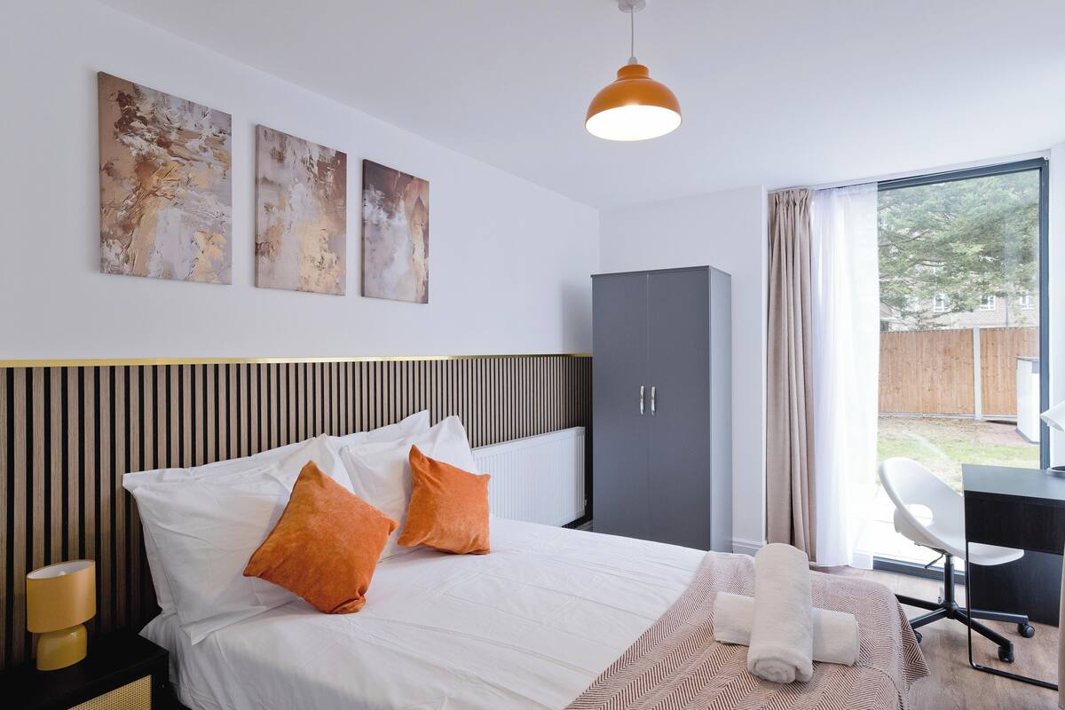 Une chambre d’hôtel avec un lit, un bureau, une chaise et des œuvres d’art accrochées au mur.