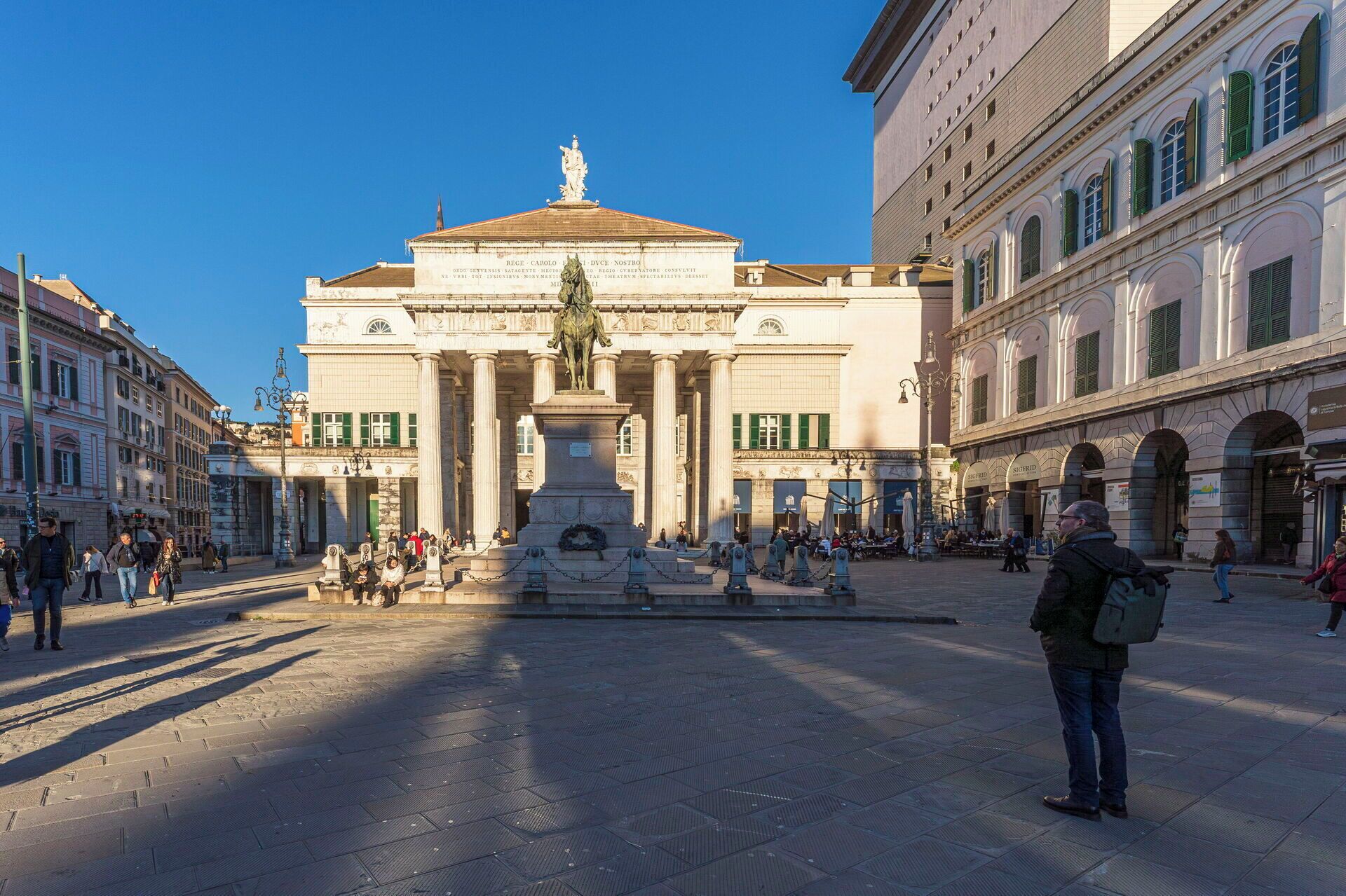A public square with a central monument and classical architecture.