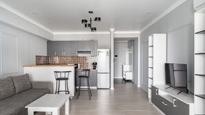 Una cocina moderna con armarios grises, encimera blanca y una lámpara de techo negra.
