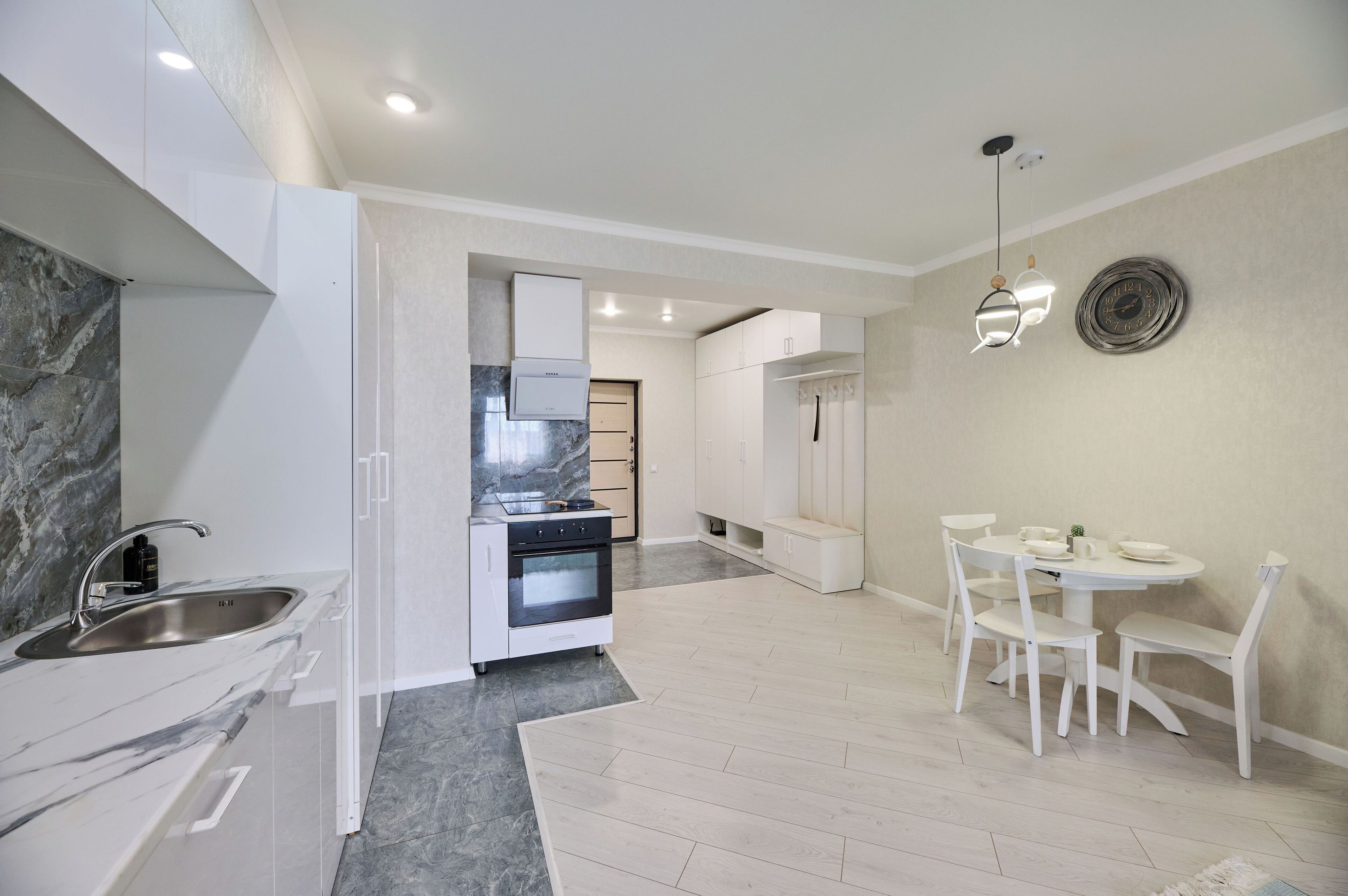 A modern kitchen with white cabinetry, a marble countertop, and a built-in oven.
