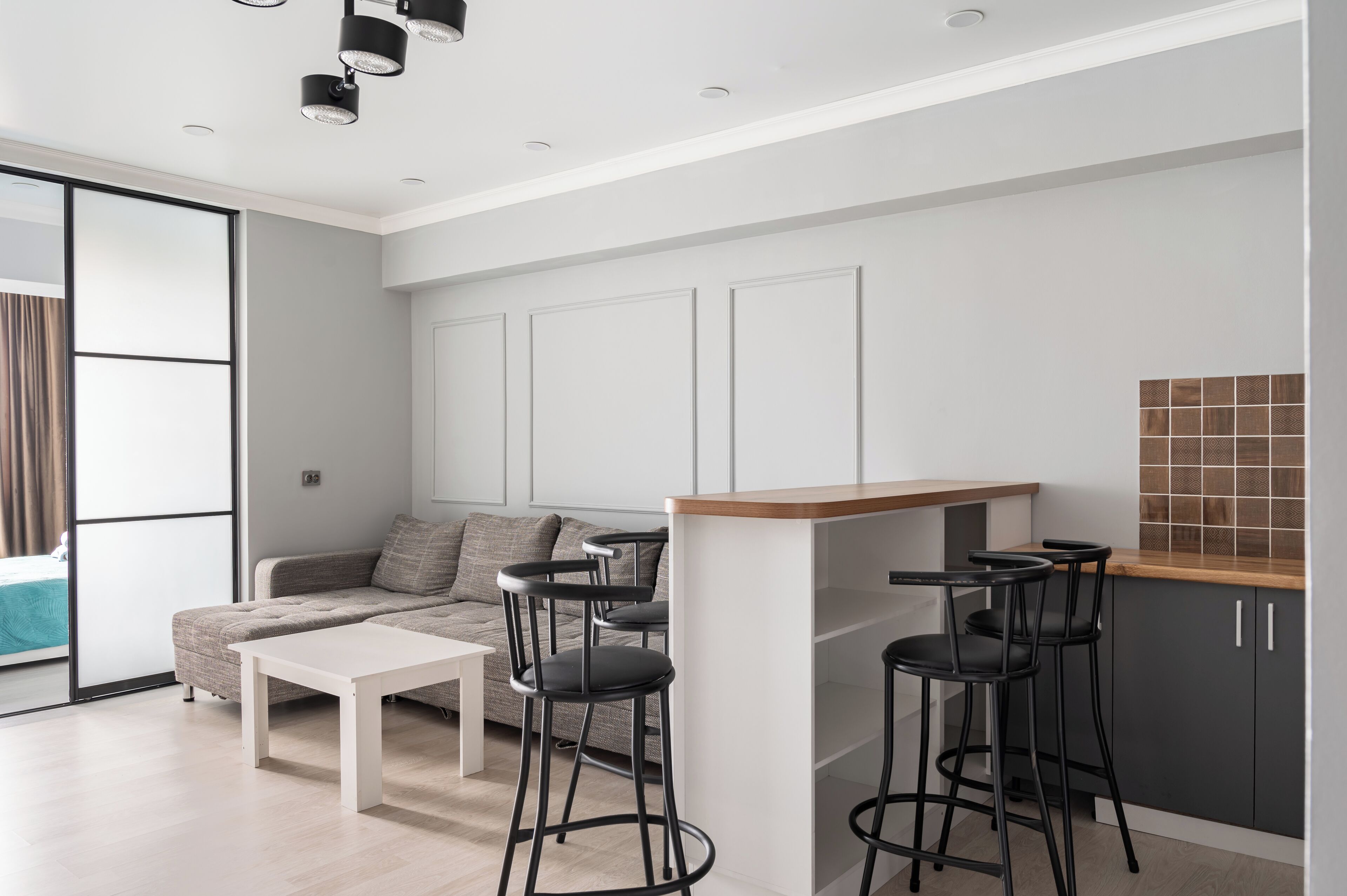 A modern kitchen with a bar area, a sofa, and a dining table.