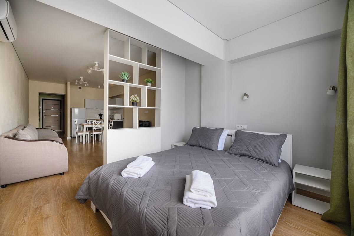 A modern bedroom with a large bed, a sofa, and a built-in shelving unit.