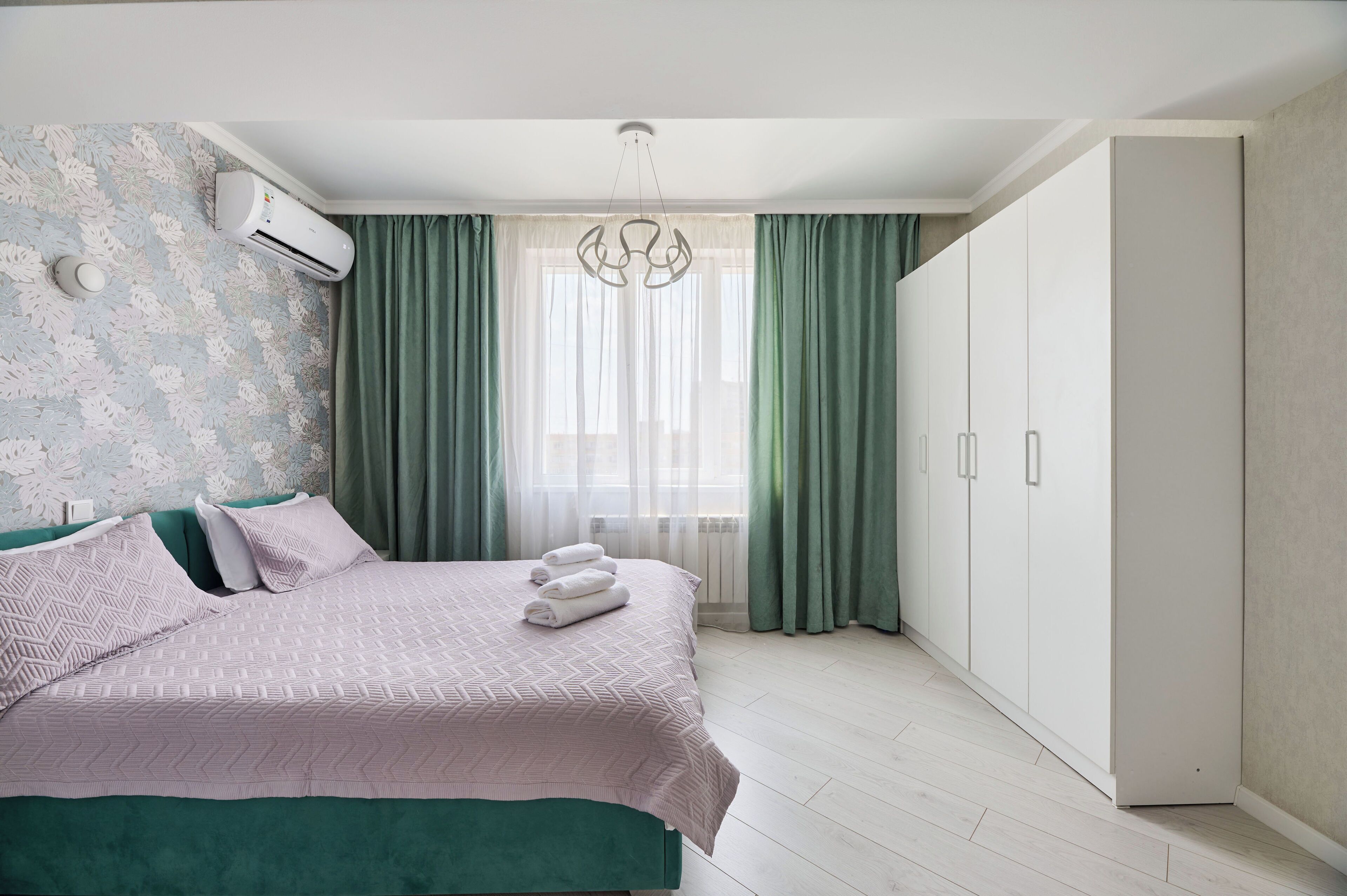 Ein Schlafzimmer mit einem Bett, einem Kleiderschrank und einem Fenster mit Vorhängen.
