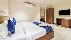 A hotel room with a bed, a TV, a wardrobe, and an air conditioning unit. - Stay Casa Inn (Jaipur)