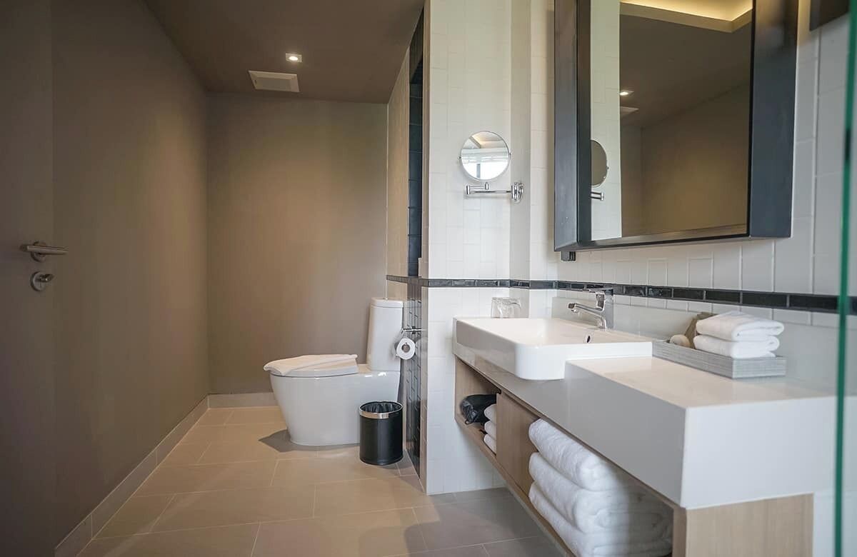 A modern bathroom with a toilet, bidet, and a large mirror above the sink.
