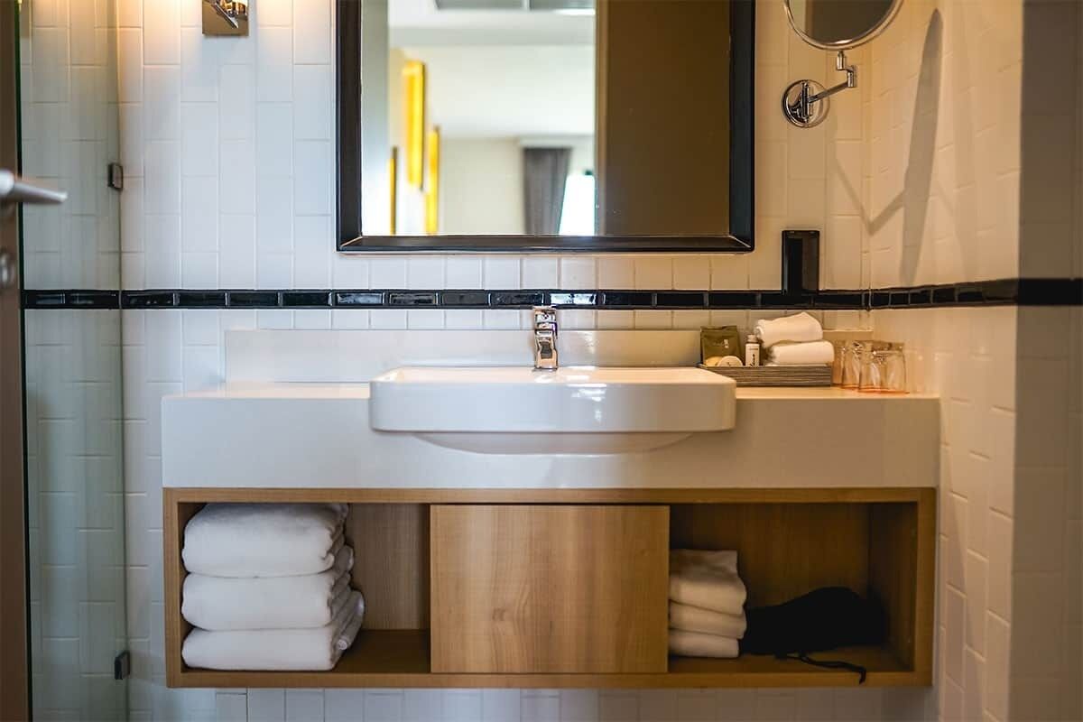 A bathroom with a white sink, a mirror, and a towel rack.
