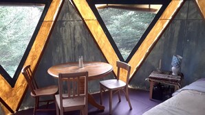 Une pièce avec une table et des chaises en bois, une petite table de chevet avec une lampe et un lit.