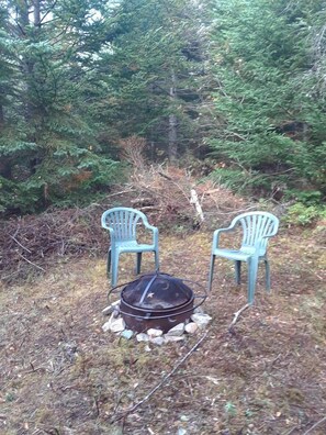 Two outdoor chairs, a metal fire pit, and a forested area. - Yurt Nestled in Nature on Community in Nova Scotia, Canada (Maple Grove)
