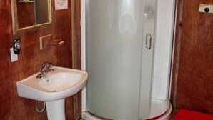 A bathroom with a white pedestal sink, a toilet, and a glass-enclosed shower. - Luxurious Woodland Cabin in Nova Scotia (Baddeck)