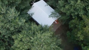 Vista aérea de un edificio pequeño y rectangular rodeado de abundante follaje verde.