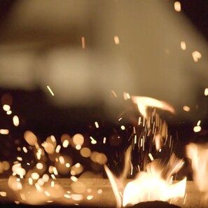 A blurred view of a room with a visible fireplace emitting sparks.