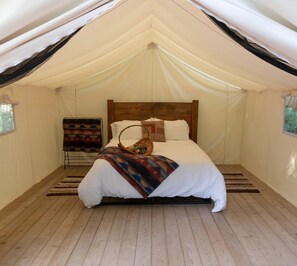 A tented room with a bed, a blanket, and a basket. - Beautiful Ontario Glamping Tent Along Lynn River (Port Dover)