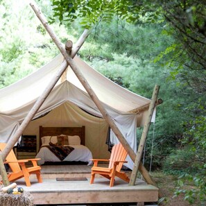 A tented accommodation with a bed, two chairs, and a view of the forest. - Beautiful Ontario Glamping Tent Along Lynn River (Port Dover)