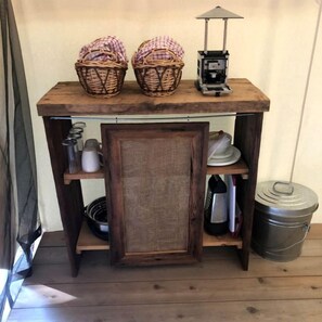 Una mesa de madera con cestas, un farolillo y utensilios de cocina.