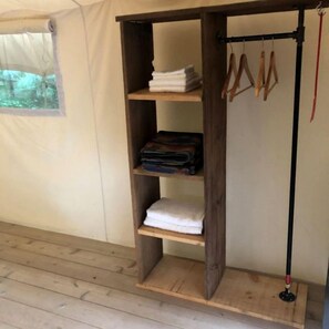 Una estantería de madera con toallas dobladas y objetos colgando.
