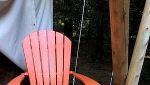 A wooden deck with a single orange Adirondack chair.