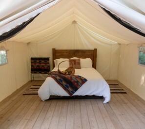 A tented room with a bed, a blanket, and a basket. - Beautiful Ontario Glamping Tent Along Lynn River (Port Dover)