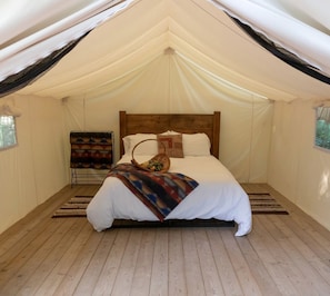 A tented room with a bed, a blanket, and a basket. - Beautiful Ontario Glamping Tent Along Lynn River (Port Dover)