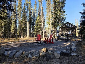 A cabin with a deck, surrounded by a forest.