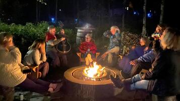 Eine Gruppe von Menschen sitzt um eine runde Feuerstelle in einer Außenanlage.