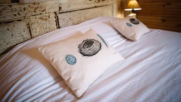 Ein Bett mit zwei Kissen mit Vogelnester-Muster, einer Lampe und einem rustikalen Holz-Kopfschild.