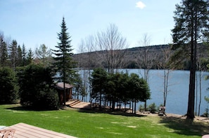 Una cabana al costat d'un llac, amb terrassa i un cobert petit.