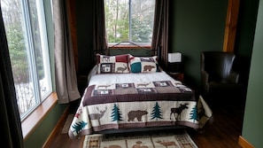 A bedroom with a bed, a window, a chair, and a nightstand.