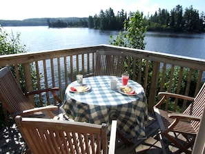 A deck with a checkered tablecloth, wooden chairs, and a table set with plates, a pitcher, and a glass of pink beverage. - Secluded Rental Perfect for a Romantic Getaway in Algonquin Park, Ontario (South River)