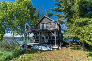 A wooden cabin with a balcony, a hammock, and a view of the lake. - Secluded Rental Perfect for a Romantic Getaway in Algonquin Park, Ontario (South River)