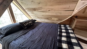 Ein Schlafzimmer mit einem Bett, einem Schachbrettmuster-Teppich und einem Kissen mit Aufschrift.